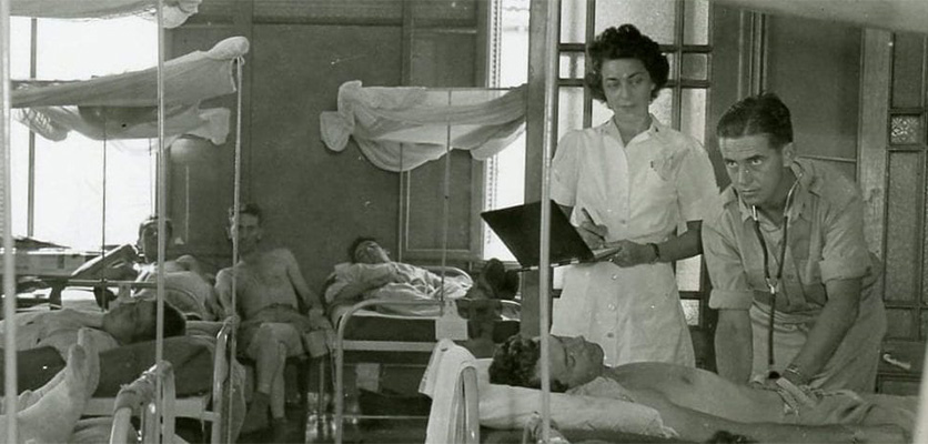 A physician and nurse check on a bedbound patient on the wards in Livorno, Italy, during WWII.