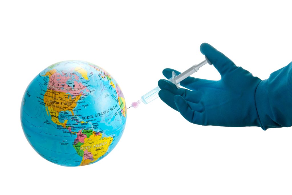 A globe being injected with a clear substance by a jet injector held by an hand in a blue glove