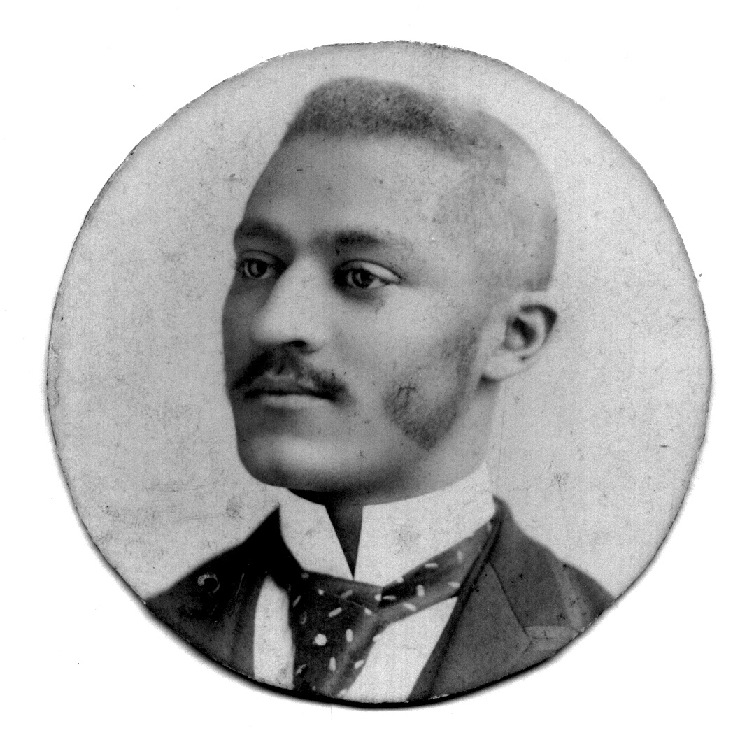 Black man with mustache and sideburns dressed in formal wear shown from shoulders up
